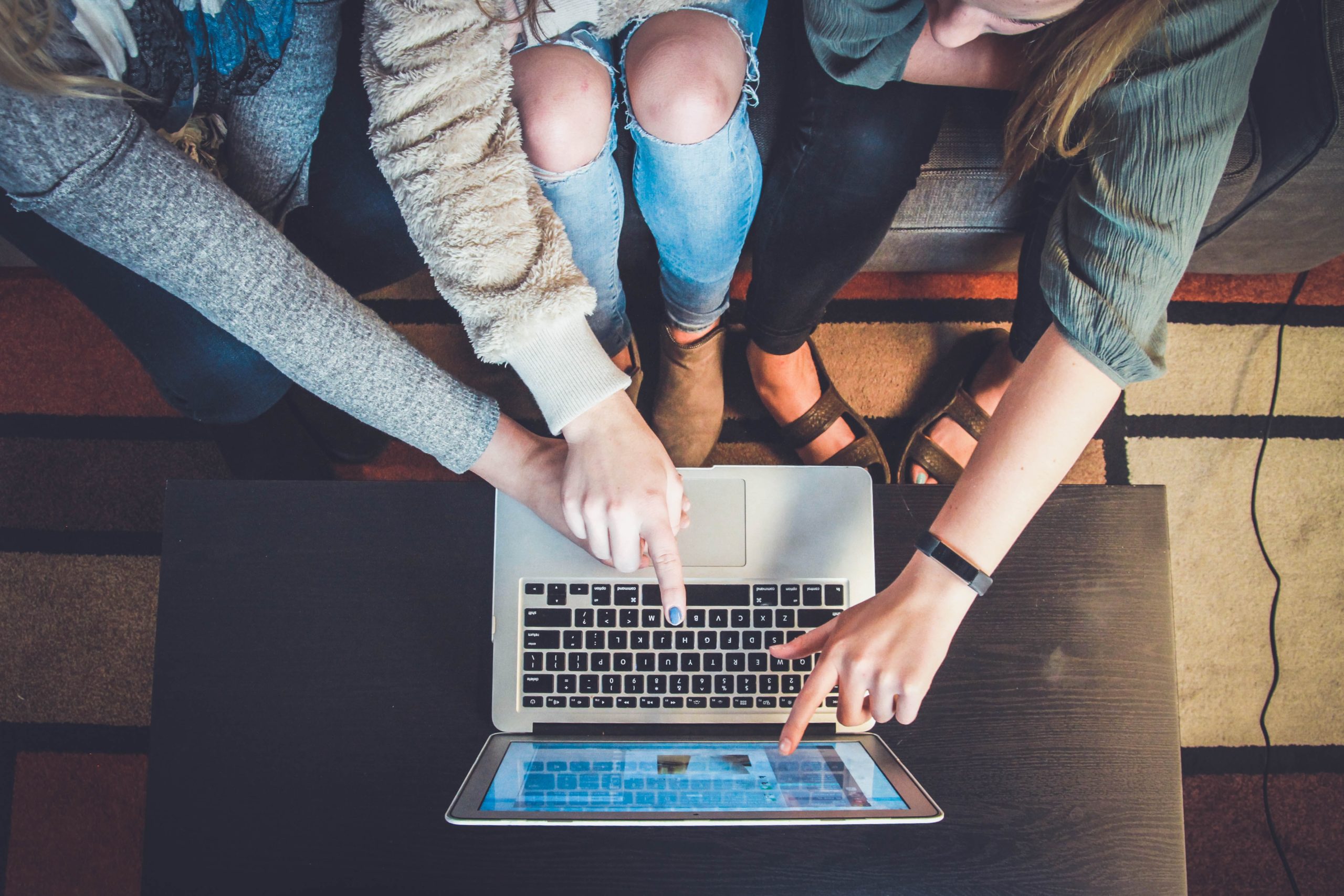 people pointing to a computer to collaborate on a joint project